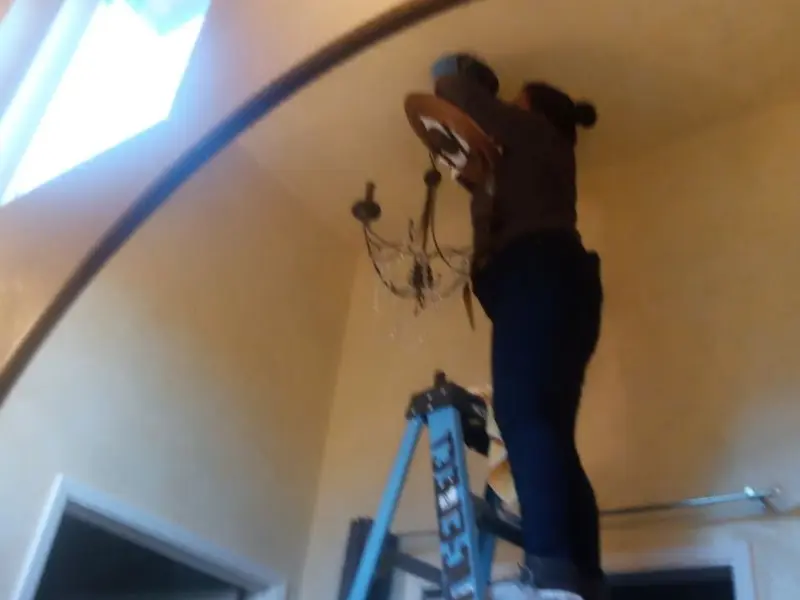 Electrician installing a chandelier in a Lumberton residence